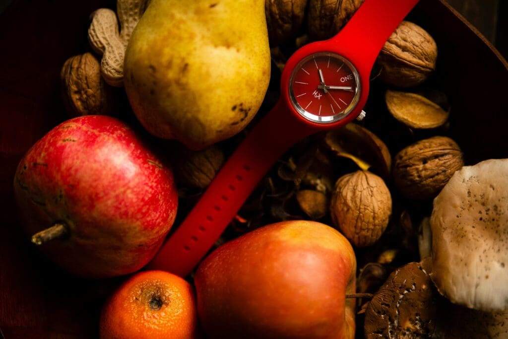 Intermittent Fasting - a red watch surrounded by fresh fruit and vegetables