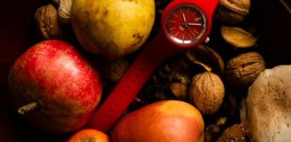 Intermittent Fasting - a red watch surrounded by fresh fruit and vegetables